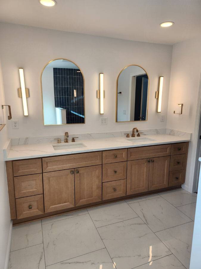 Bathroom with gold arched mirrors and marble tile