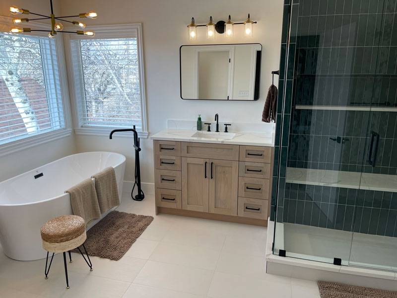 Freestanding soaking tub beside a teal tile shower